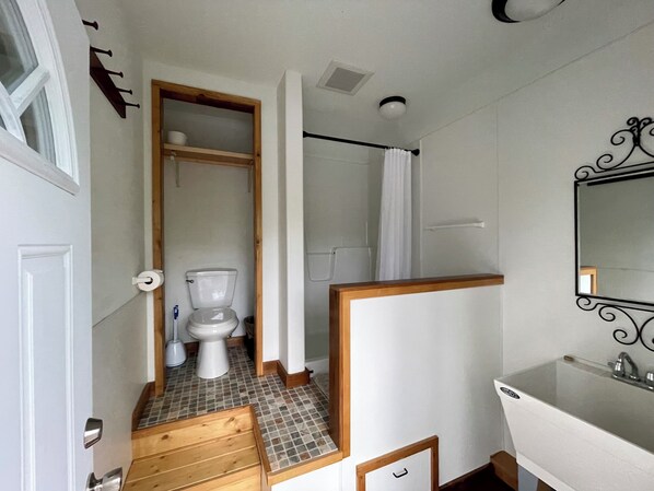 A bathroom with a toilet, shower, and sink.