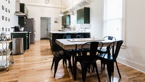 A modern kitchen with a dining area, wooden flooring, and pendant lighting.