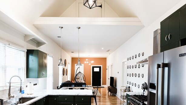 A modern kitchen with a central island, stainless steel appliances, and a wooden floor.