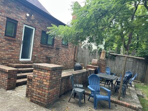 A backyard with a brick patio, outdoor seating, and a wooden fence. - Welcome to “The Spot” - North Limestone/Downtown! (Lexington)