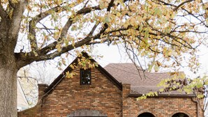 A brick house with a gabled roof, a front door, and a small porch area.