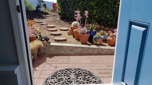 A view of a garden with various potted plants and a red chair. - Cozy, modern 1-bedroom guest suite with backyard ocean view! (Pacifica)