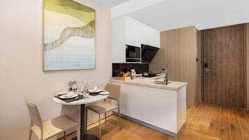 A modern kitchen with a central island, a dining area with a round table, and a large abstract painting on the wall.