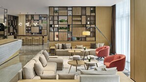 A modern hotel lobby with a bar, seating area, and a wooden bookshelf. - Hyatt Place Shanghai Lingang (Shanghai)