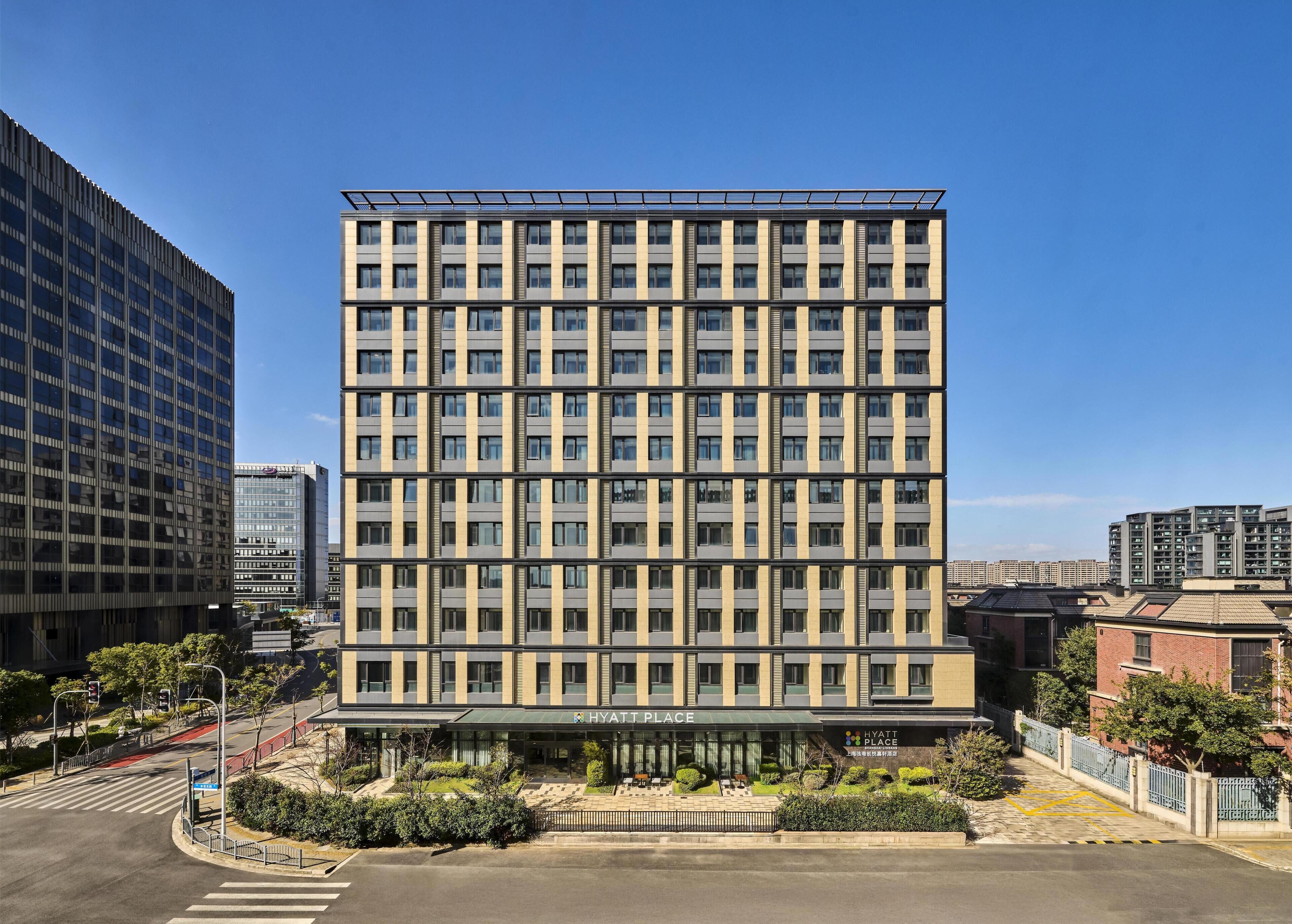 Een hotel met meerdere verdiepingen, een moderne gevel, grote ramen en een duidelijke ingang met een bord.