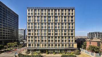Een hotel met meerdere verdiepingen, een moderne gevel, grote ramen en een duidelijke ingang met een bord.