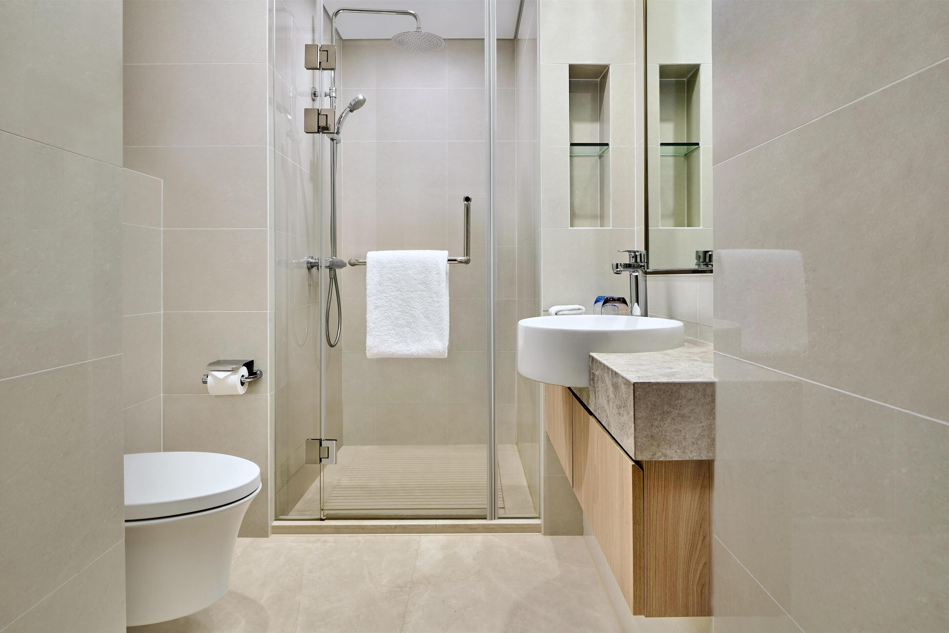 Une salle de bain moderne avec une douche à parois de verre, des toilettes, un lavabo et un miroir.