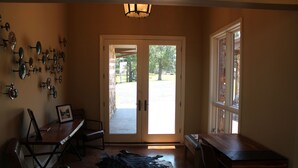 A room with a wooden table, a bench, a cowhide rug, and a wall-mounted light fixture. - LAKEFRONT ON GRAND LAKE “THE LODGE” AT STONY POINT (Jay)