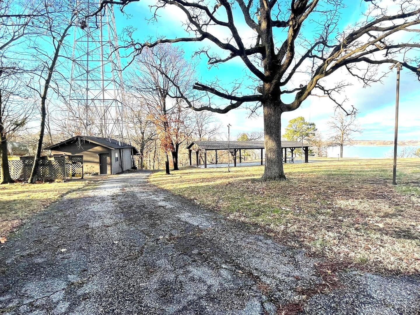 A gravel path leading to a building with a covered porch, surrounded by trees and a clear sky.