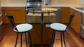 A modern kitchen with wooden cabinets, stainless steel appliances, and two bar stools. - LAKEFRONT ON GRAND LAKE “THE LODGE” AT STONY POINT (Jay)