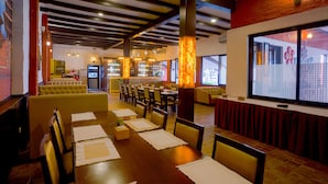 A restaurant with wooden tables, yellow booths, and a brick wall. - Hukum Darbar Restaurant & Hotel (Kathmandu)