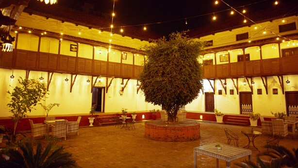 A courtyard with a central tree, surrounded by tables and chairs, under string lights. - Hukum Darbar Restaurant & Hotel (Kathmandu)