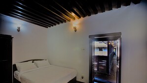 A bedroom with a bed, wooden flooring, and a hallway leading to a staircase. - Hukum Darbar Restaurant & Hotel (Kathmandu)