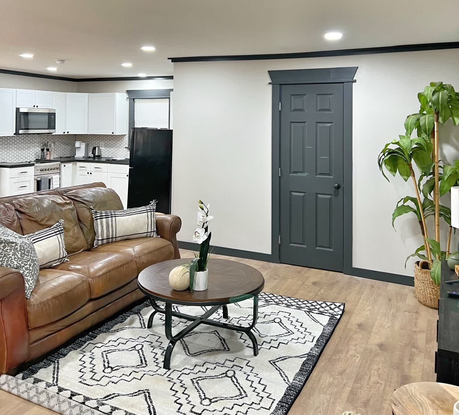 A modern living room with a leather sofa, a round coffee table, and a patterned rug.