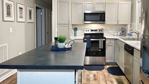 A modern kitchen with stainless steel appliances, a central island, and a view of the adjacent living area. - Corporate Stay: 5BR, Guest Suite & Fast WiFi (Decatur)