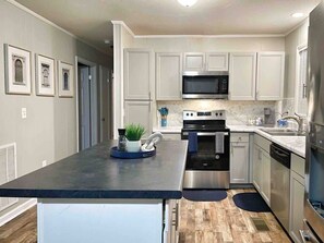 Una cocina moderna con electrodomésticos de acero inoxidable, una isla central y vistas al área de estar contigua.