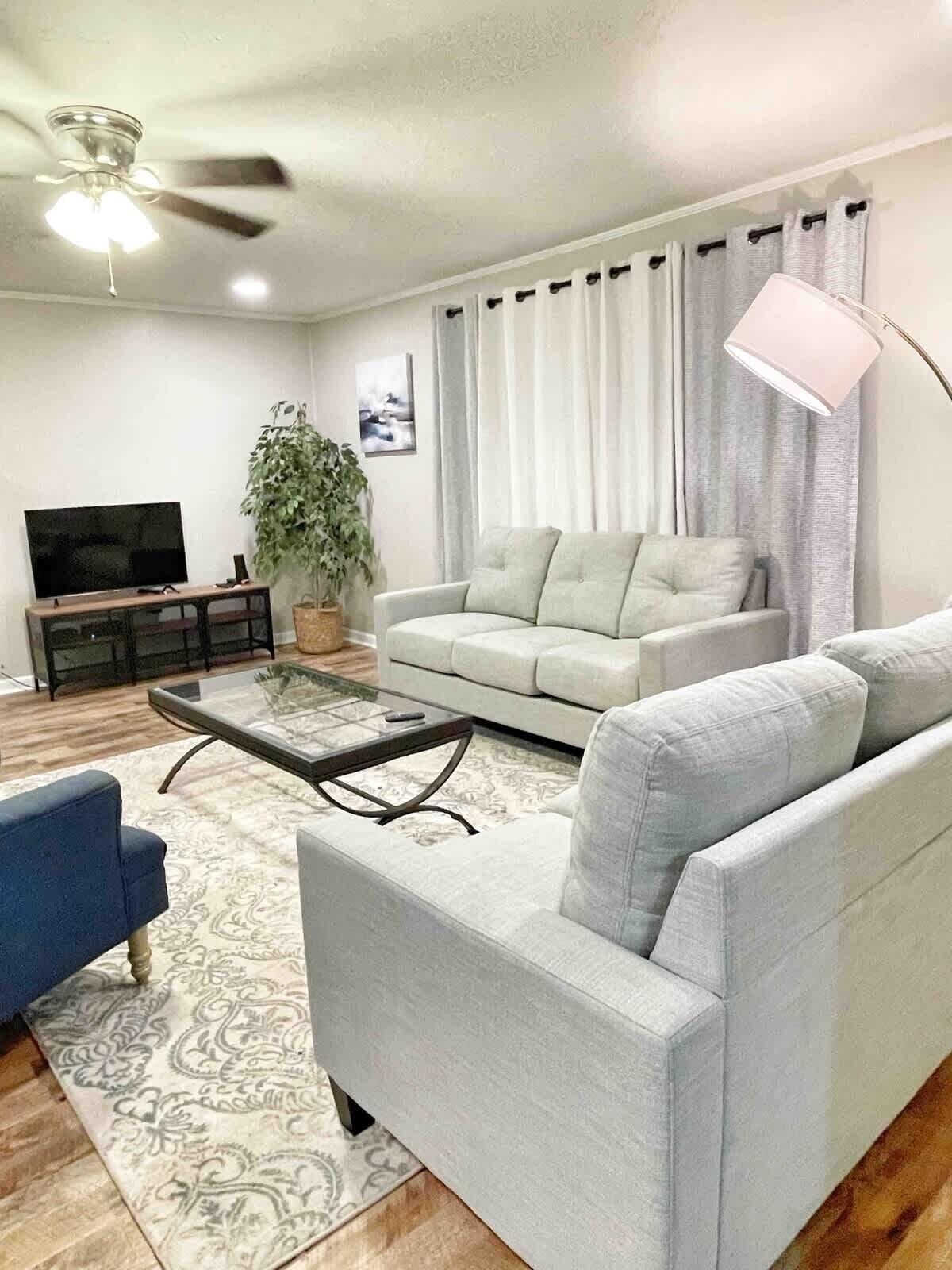 Ein Wohnzimmer mit Sofa, Couchtisch, Fernseher und Deckenventilator.