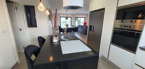 A modern kitchen with a central island, stainless steel appliances, and a dining area with a view.