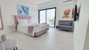 A modern bedroom with a large bed, a grey sofa, and a small side table. - Sky Villa by Laranjal Rentals (Albufeira)