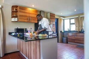 A modern kitchen with wooden cabinets, a black countertop, and a person preparing food.