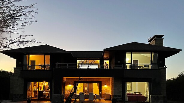 Una casa moderna de dos pisos con ventanas grandes y un balcón.