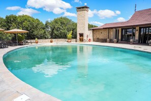 A swimming pool with a stone tower, lounge chairs, and a building with large windows.