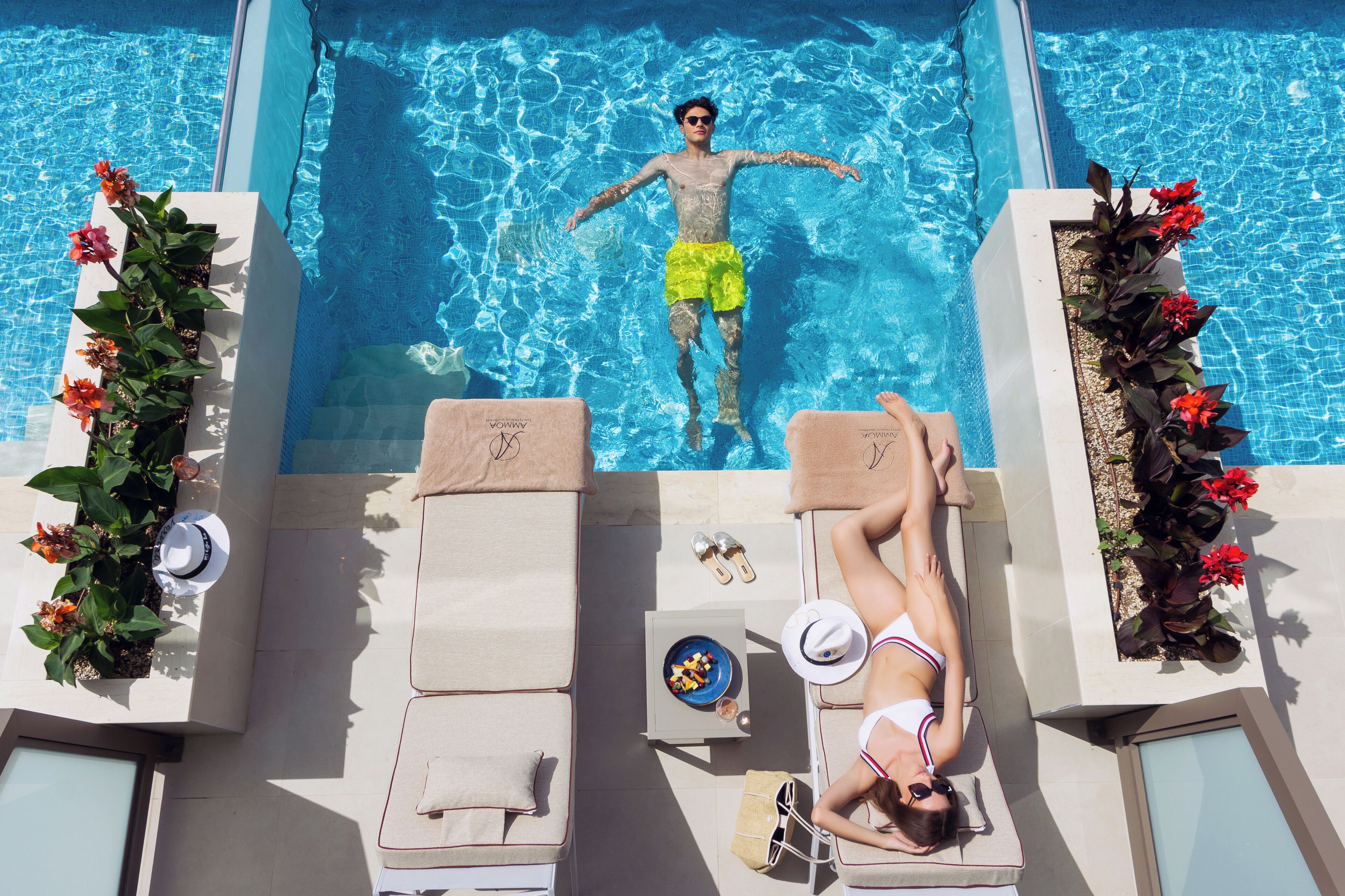 A poolside area with lounge chairs, a pool, and potted plants.
