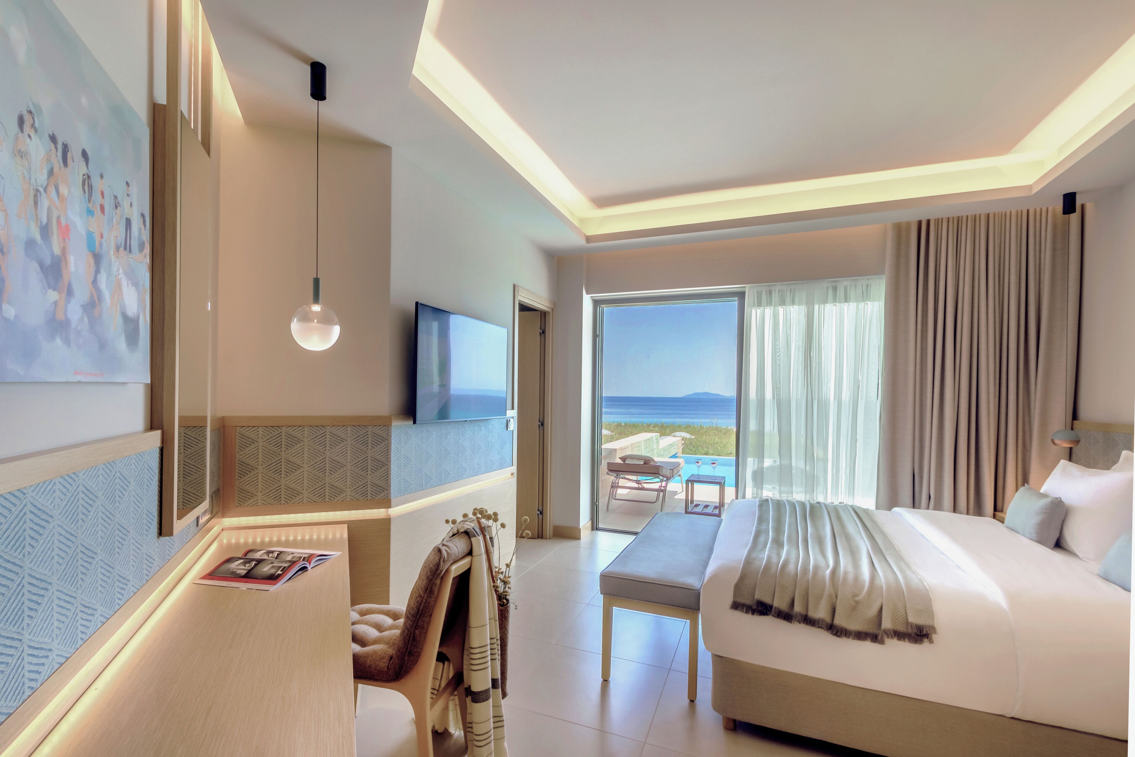 A hotel room with a bed, a desk with a chair, a TV, and a view of the ocean.