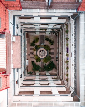 Ein Innenhof mit einer zentralen Wendeltreppe, umgeben von Pflanzgefäßen und einem gefliesten Boden.