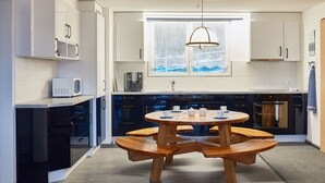 Una cocina moderna con armarios blancos, una mesa redonda de madera y un ventanal con vistas.