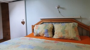 A bedroom with a wooden headboard, two pillows, an orange bedspread, and a white door. - Elfe - Apartments Studio Apartment for 2-4 Guests With Amazing View (Emmetten)