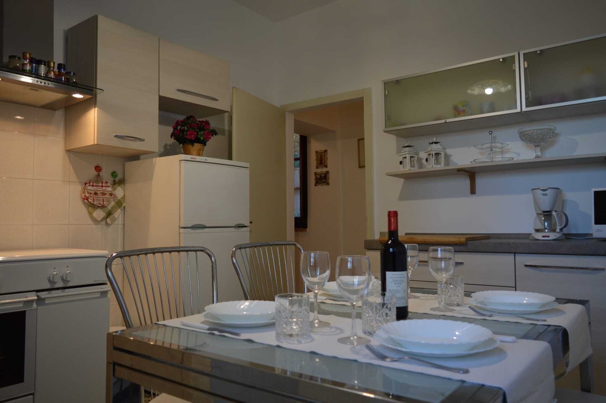 Un comedor con una mesa dispuesta para cuatro personas, un refrigerador, un microondas y una cafetera.