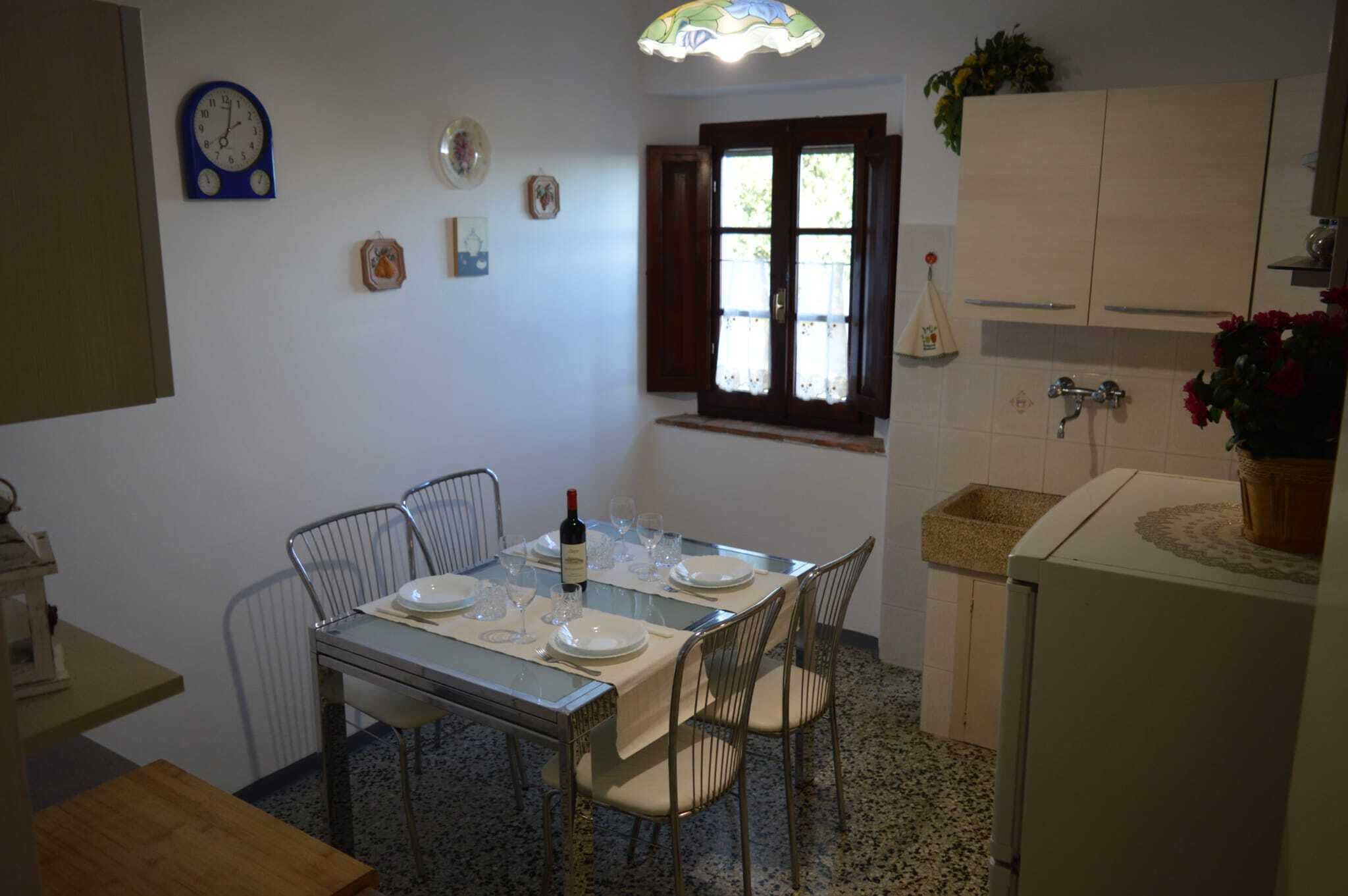 A dining area with a table set for two, a clock, and a window with curtains.