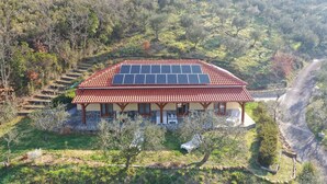 A house with a red-tiled roof, solar panels, and a stone foundation. - Ecolodge Selvitelle - Sustainable Retreat Amidst Olive Groves in Cilento (Cicerale)