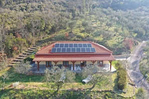 A house with a red-tiled roof, solar panels, and a stone foundation.