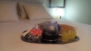 A neatly made bed with white linens, a tray with a teapot, cups, and glasses of orange juice. - Beautiful Petrino 1880 (Sithonia)