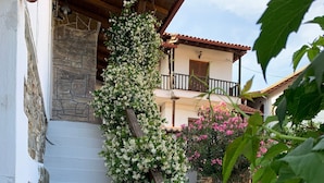 A staircase with white walls and stone steps, surrounded by lush greenery and flowering plants. - Beautiful Petrino 1880 (Sithonia)