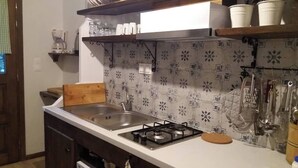 A kitchen with a gas stove, a sink, and a patterned backsplash. - Beautiful Petrino 1880 (Sithonia)