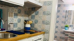 Cozinha com bancada de madeira, armários brancos e painel de azulejos estampados.