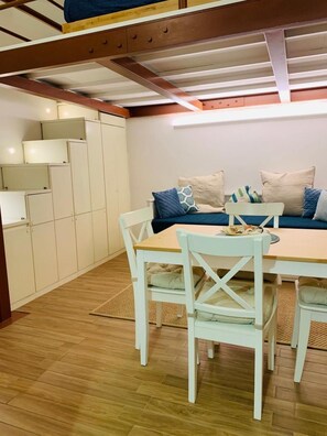 A cozy room with a dining table, chairs, a sofa with cushions, and a set of cabinets. - Trastevere Tourist Accommodation Stay in the Heart of Rome (Rome)