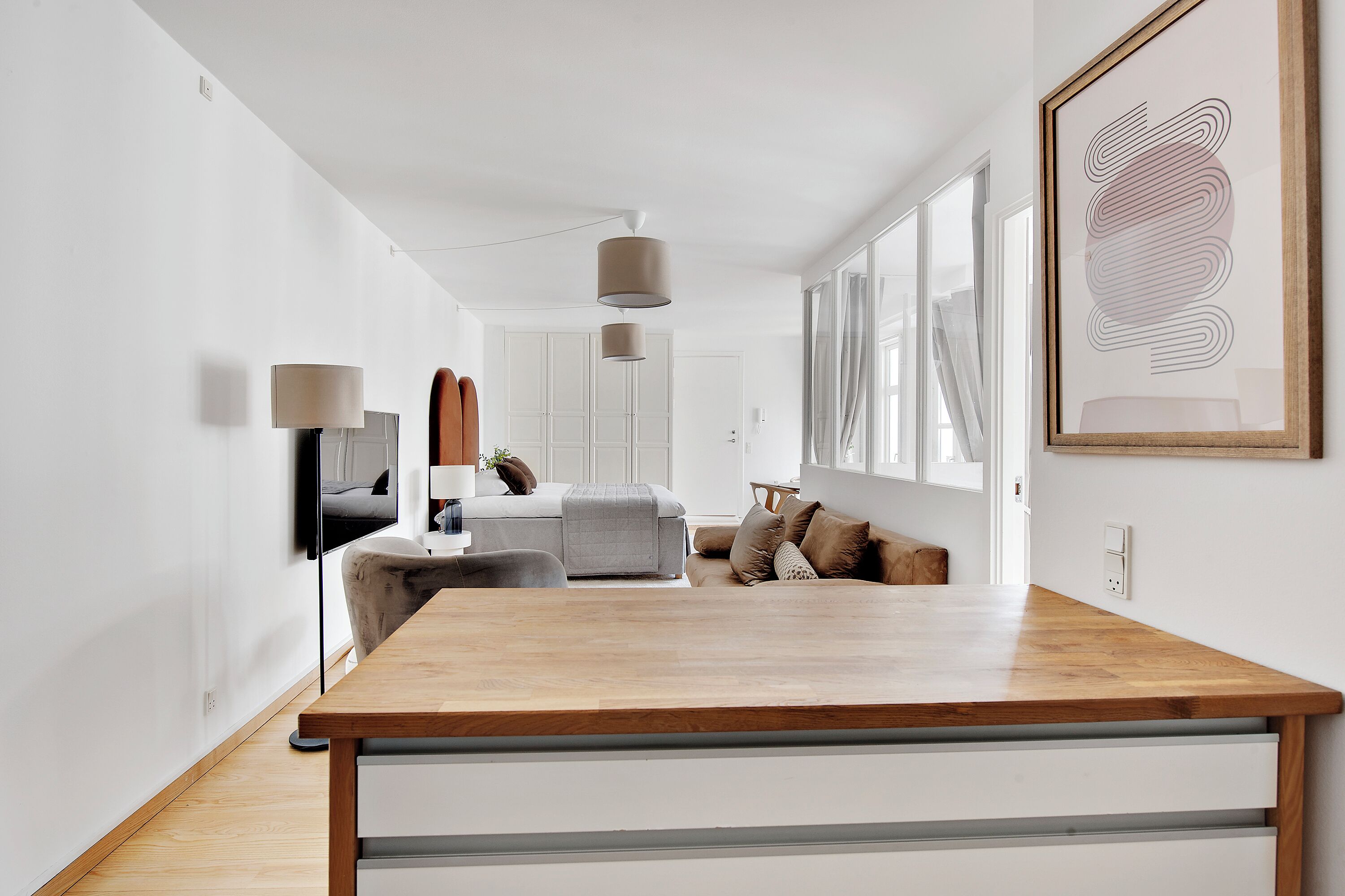 Un salon moderne avec une table à manger en bois, un canapé et un téléviseur fixé au mur.