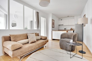 A modern living room with a sofa, a chair, a small table, and a floor lamp.