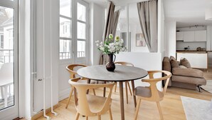 A modern living room with a round wooden table and chairs, a beige sofa, and a vase of flowers. - City 3 - Popular 1-bdr Apt In the Center of Copenhagen (Copenhagen)