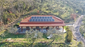 A house with a red-tiled roof, solar panels, and a stone foundation.