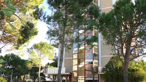 A modern building with a glass facade, surrounded by a well-maintained lawn and trees. - Vacation by the Beach-beahost (Caorle)