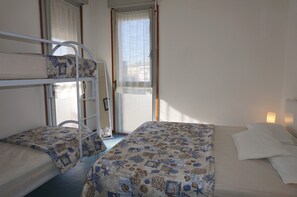 Une chambre avec des lits superposés, une fenêtre avec des rideaux et une lampe de chevet.