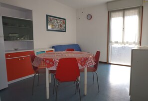 Ruokailutila, jossa on pöytä, tuoleja, kello ja ikkuna, jossa on verhot.