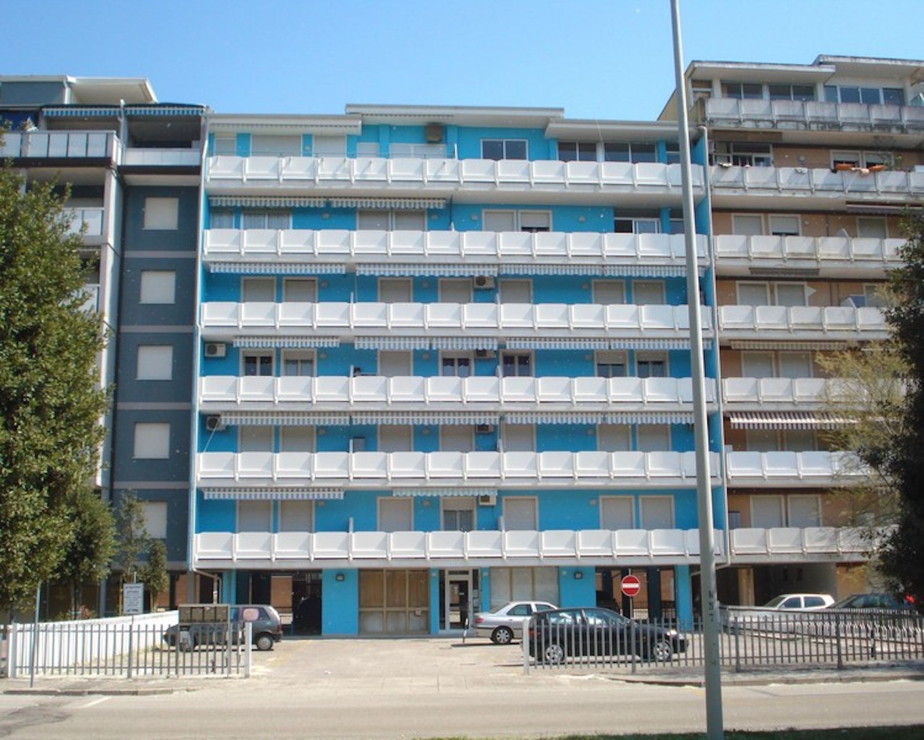 A multi-story hotel with balconies, a parking area, and a no-entry sign.