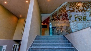 Una escalera con barandilla de vidrio y pared decorada.