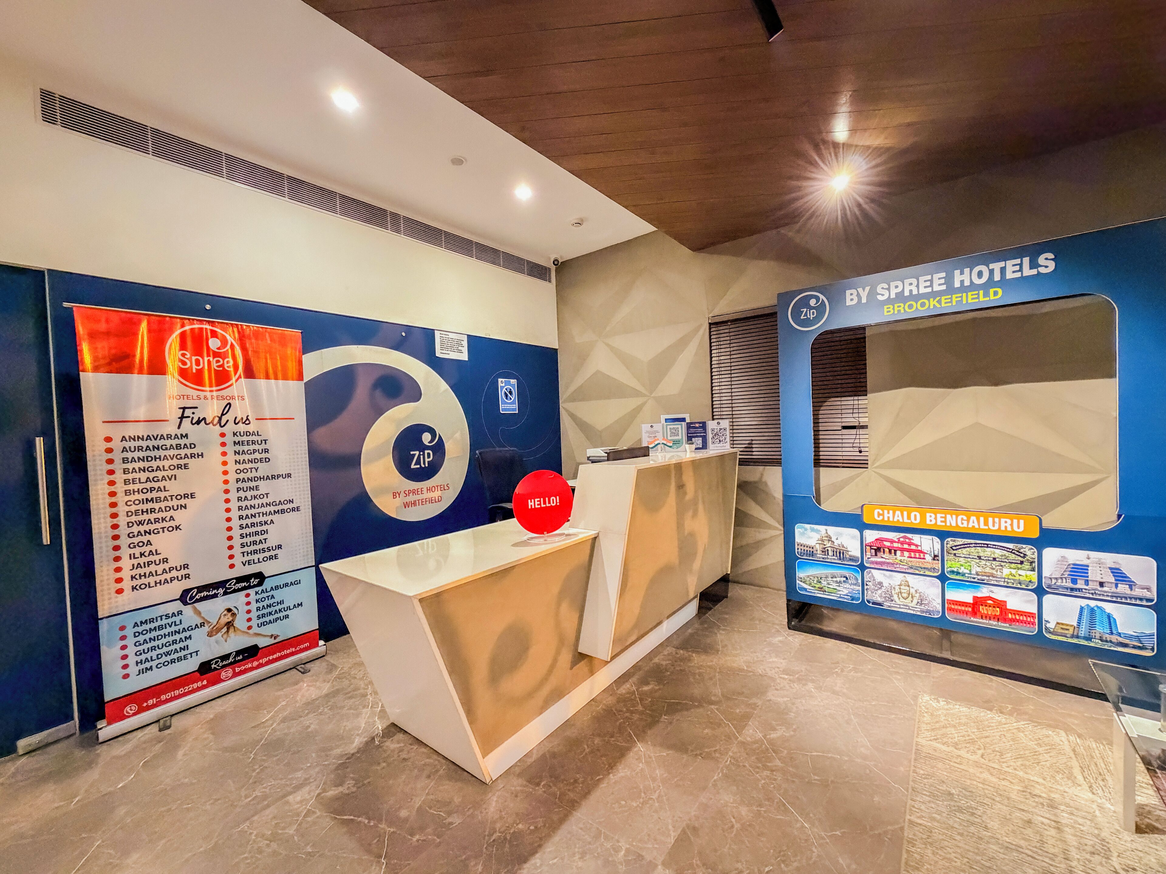 A hotel reception area with a reception desk, a large Spree Hotels sign, and a wall with a map and pictures of local attractions.